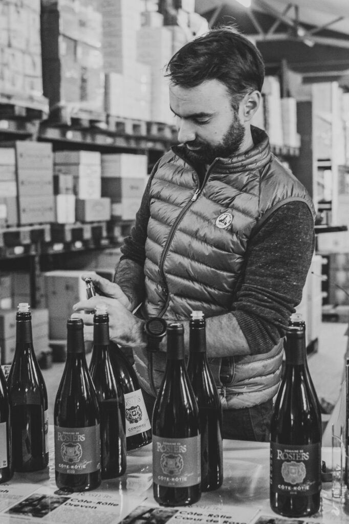 Viticulteur organise bouteilles de vin dans un entrepôt.